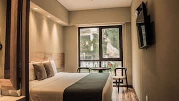 Une chambre à coucher comprenant un lit, une chaise, une table et un téléviseur fixé au mur.