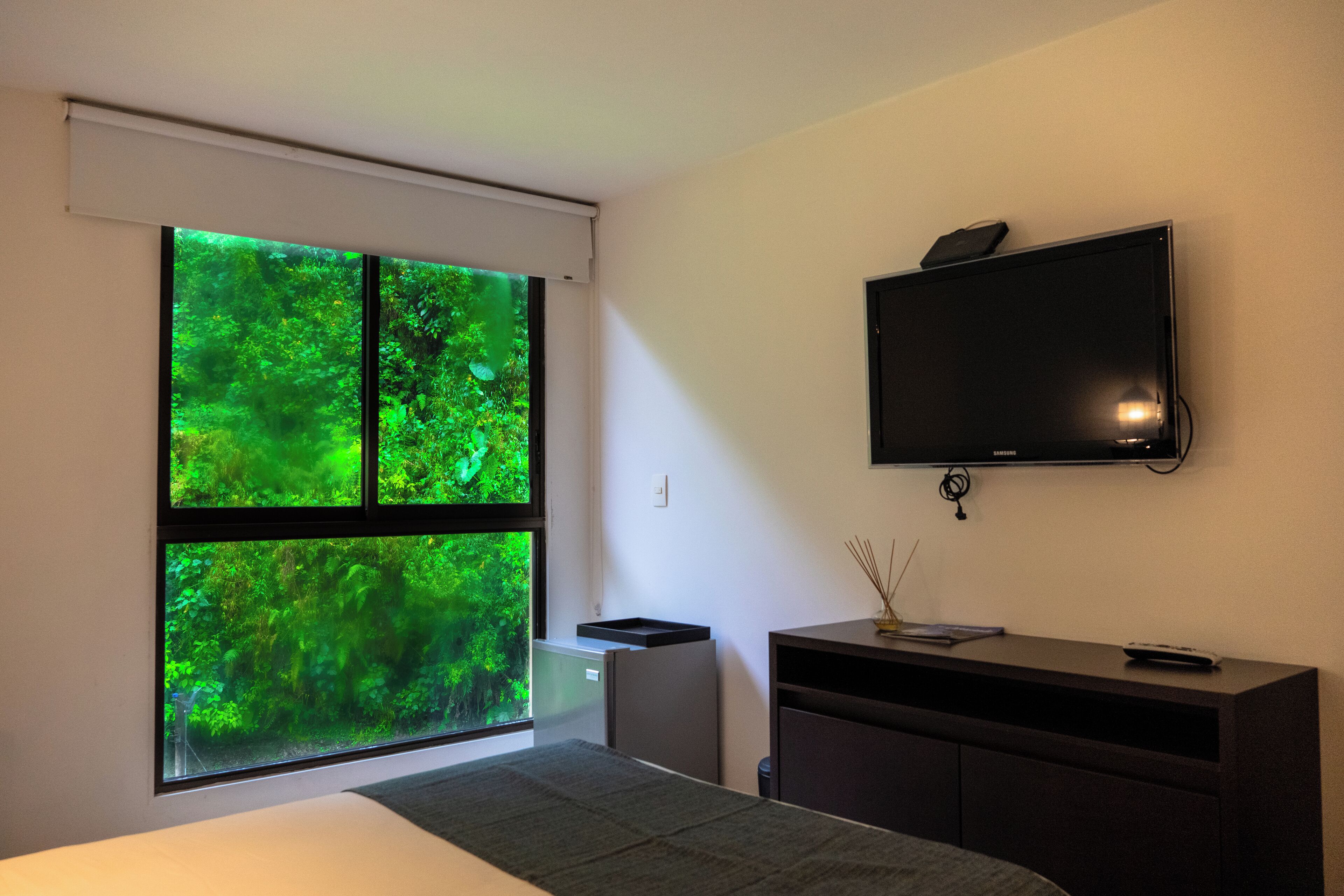 A modern bedroom with a large window, a flat-screen TV, and a minimalist design.