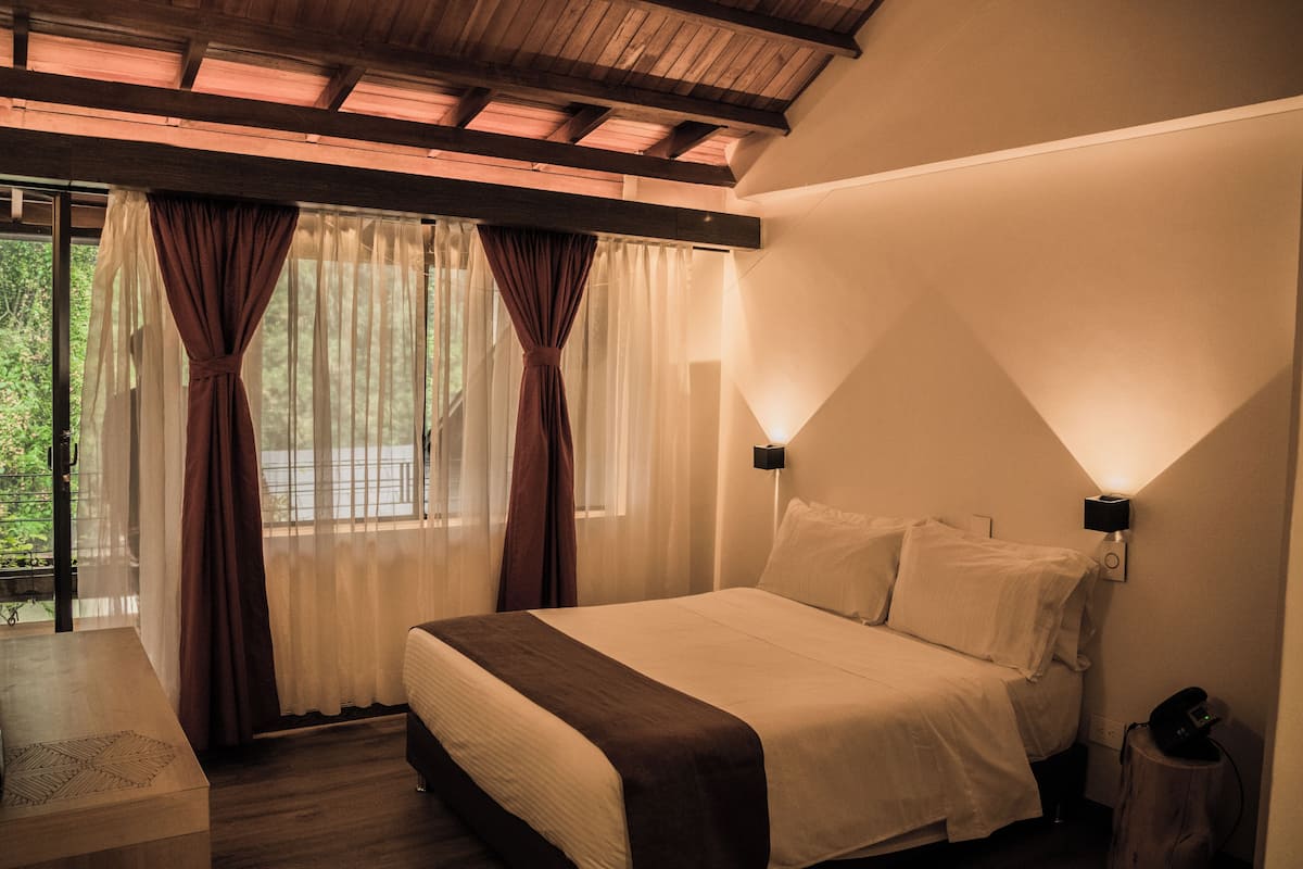 Ein Schlafzimmer mit einem Bett, Vorhängen, einem Nachttisch und einem Beistelltisch.
