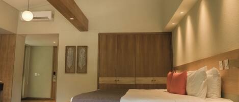 A modern bedroom with a wooden headboard, a large bed with white and pink pillows, and a wooden wardrobe.