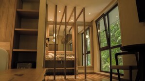 A modern bedroom with a large window, wooden beams, a built-in bed, and a small seating area. - Termales Santa Rosa de Cabal - Hotel  (Santa Rosa de Cabal)