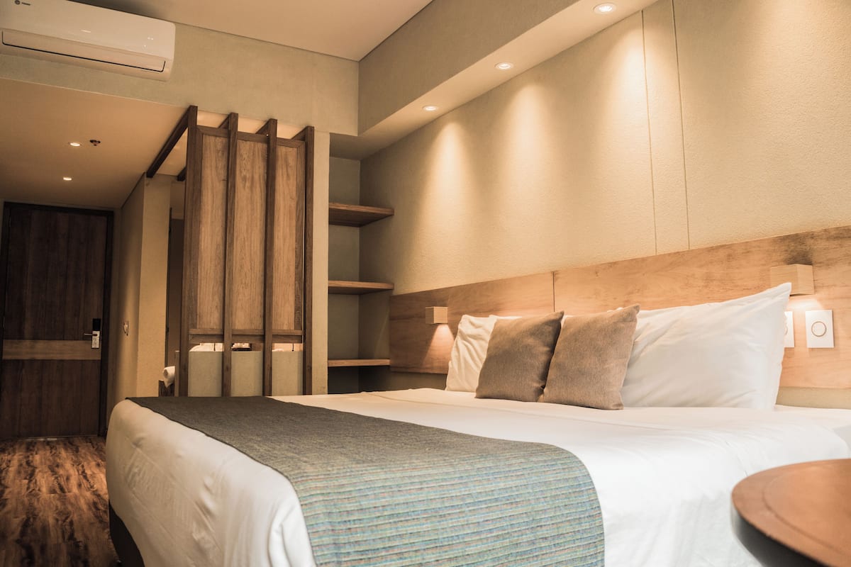 Ein modernes Hotelzimmer mit einem großen Bett, einem Holzkopfteil und einem Einbauschrank.