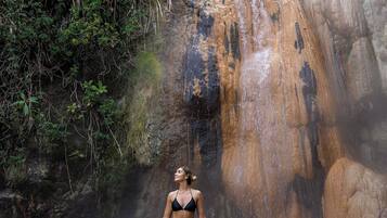 Una mujer en traje de baño de pie en el agua cerca de una cascada.