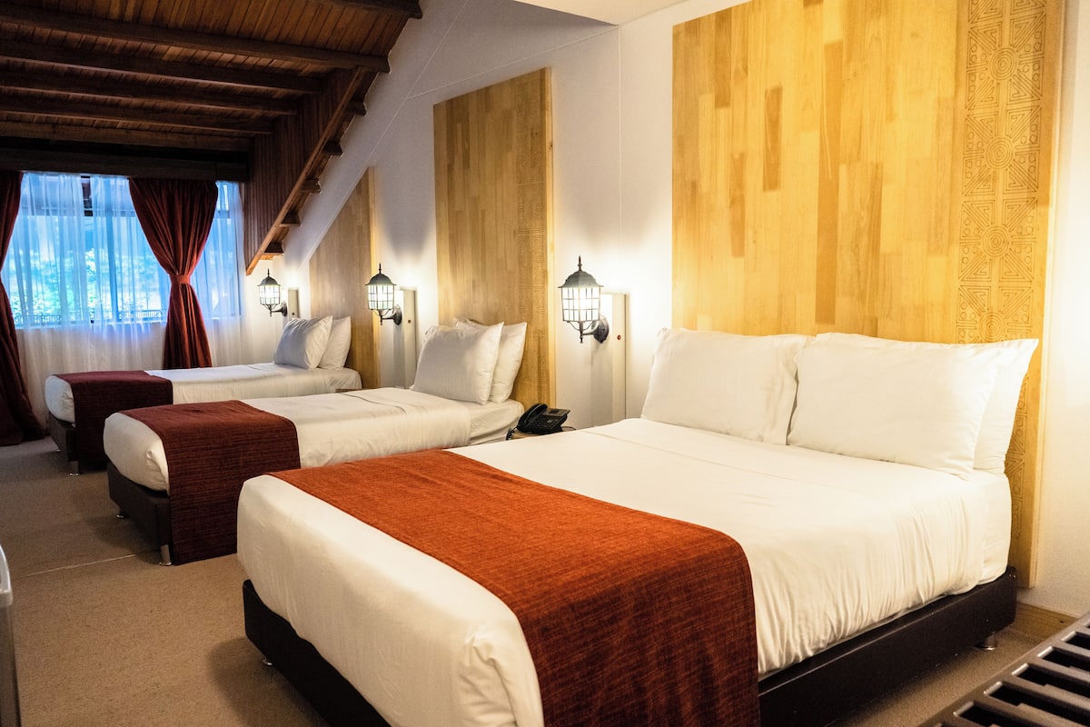 Ein Hotelzimmer mit zwei Betten, einem Holz-Kopfteil und Wandleuchten.