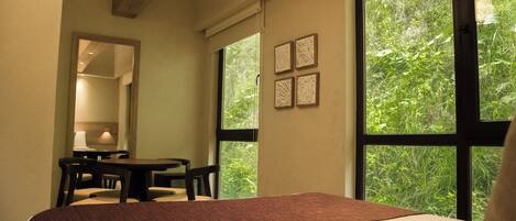 A bedroom with a large bed, a desk, and chairs. There are four framed pictures on the wall.