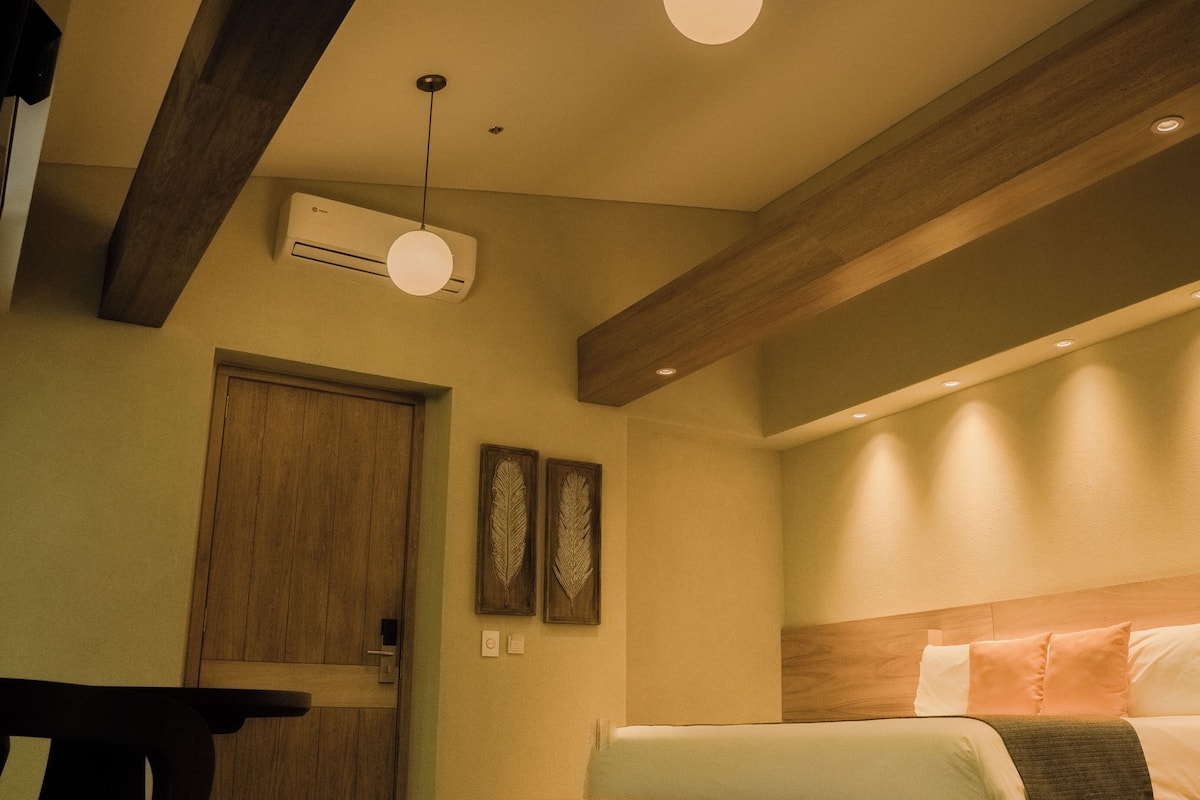 Ein Hotelzimmer mit Bett, einer Holztür, einer Wandklimaanlage und einer Deckenleuchte.
