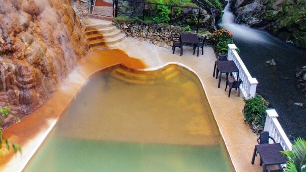 A hot spring area with a pool, outdoor seating, and a waterfall. - Termales Santa Rosa de Cabal - Hotel  (Santa Rosa de Cabal)