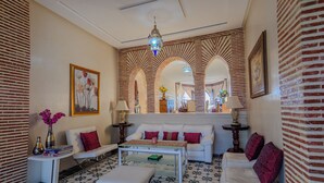 A living room with a sofa, armchairs, a coffee table, a patterned floor, and a decorative mirror. - La Terra Rosa (Ghmate)