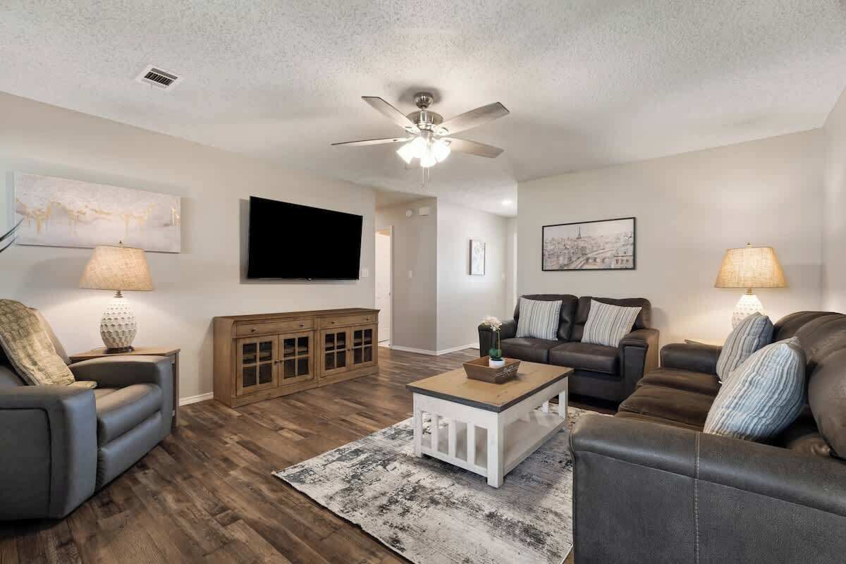 A living room with a ceiling fan, a flat-screen TV, and a wooden cabinet.