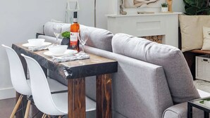 Ein moderner Essbereich mit einem Holztisch, grau gepolsterten Stühlen und einer großen Pendelleuchte.