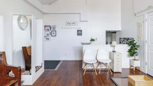 Ein modernes Interieur mit Holzboden, weißen Wänden, einem Schreibtisch mit Stühlen, einer Pflanze und einem Spiegel.