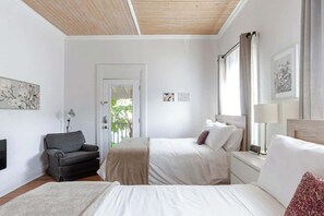 A bedroom with two beds, a sofa, a chair, and artwork on the walls.