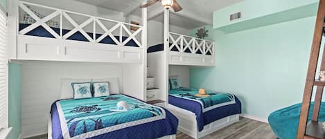 A room with two bunk beds, a ceiling fan, and a wooden floor.