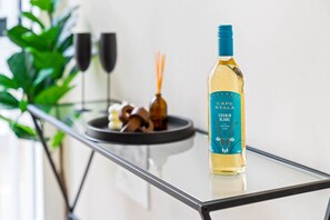 A bottle of Cape Kylala Chenin Blanc wine on a glass table with a plate of nuts and two glasses in the background.