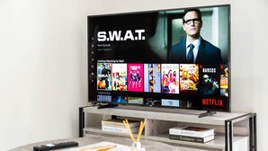 A television displaying the show S.W.A.T. on Netflix, with a remote control and books on a side table. - Luxury 2 Bed Apartment - Smart TV - WIFI (Birmingham)