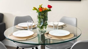 A round glass table with four white plates, each with a gold placemat, and a clear glass vase with flowers in the center. - Luxury 2 Bed Apartment - Smart TV - WIFI -  Jewellery Quarter (Birmingham)