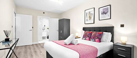 A modern bedroom with a bed, bedside table, and a desk with a chair.