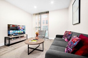 A modern living room with a flat-screen TV, grey sofa, and a coffee table. - Luxury 2 Bed Apartment - Smart TV - WIFI -  Jewellery Quarter (Birmingham)