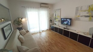 A living room with a sofa, a TV, and a potted plant. - Apartment Ana with sea view - Two Bedroom Apartment with Terrace and Sea View (Crikvenica)
