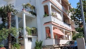 A multi-story building with balconies, potted plants, and a parked car. - Apartment Ana with sea view - Two Bedroom Apartment with Terrace and Sea View (Crikvenica)