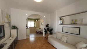 A living room with a sofa, a TV, and a dining area with a table and chairs. - Apartment Ana with sea view - Two Bedroom Apartment with Terrace and Sea View (Crikvenica)