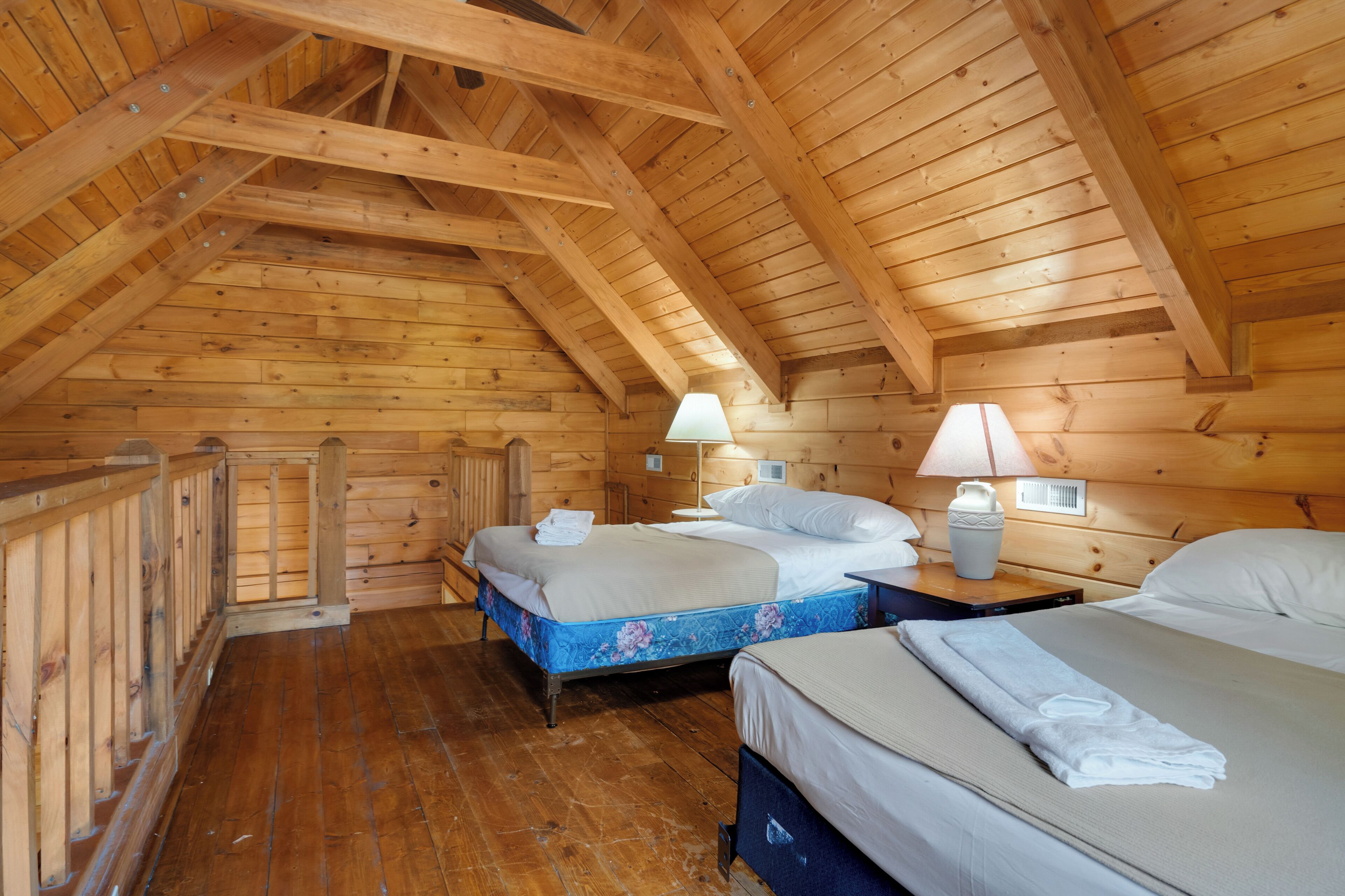 Eine Holzhütte mit zwei Betten, Holzdielenboden und schrägem Dach.