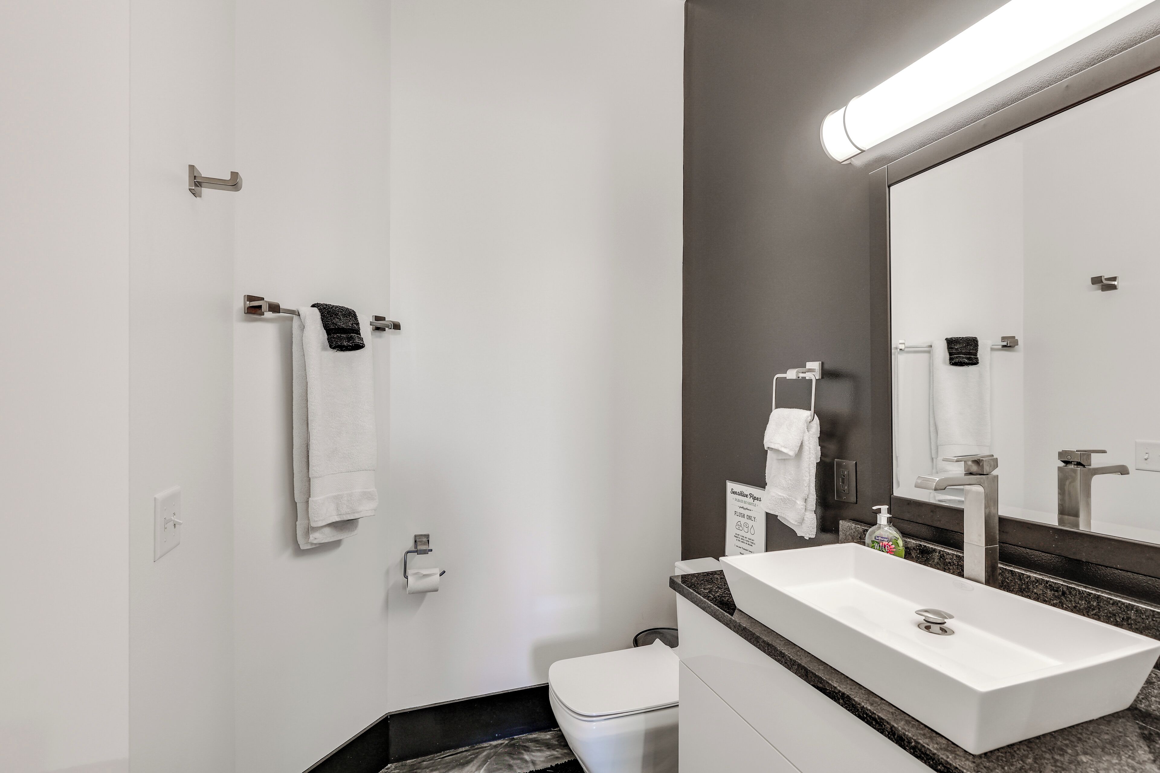 Een moderne badkamer met een wit wastafel, een spiegel en een toilet.