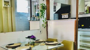 Un comedor con mesa de vidrio, cuatro sillas y un espejo en la pared.