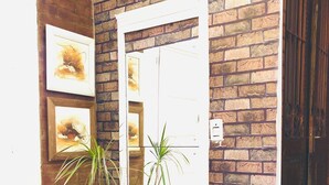 Un pasillo con una pared de ladrillo, una puerta blanca y dos plantas en macetas.