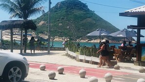 Un área pavimentada con bolardos, un coche estacionado y una montaña al fondo.