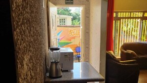 A kitchenette with a blender and a coffee maker, a sign for the emergency exit, and a mural in the background. - Hostel Dumah (São Paulo)