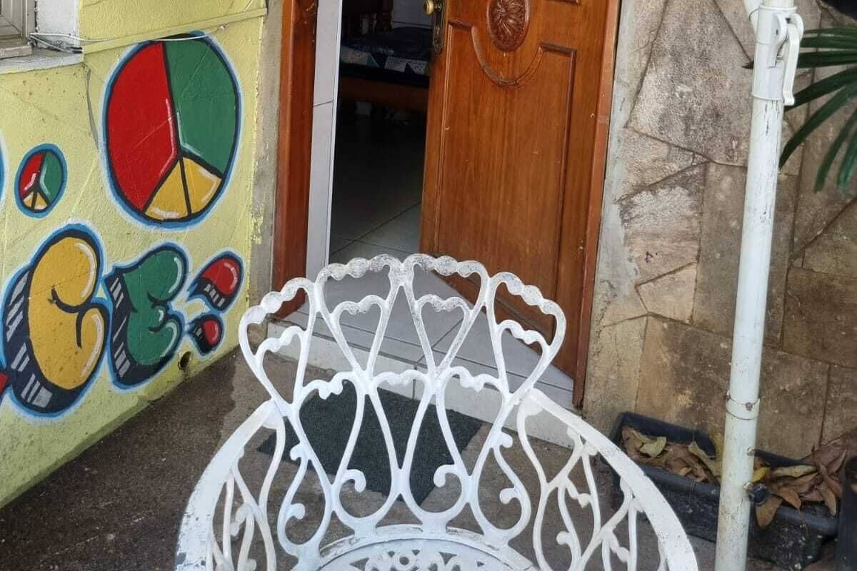 Eine Holztür mit einer verzierten Klinke, ein weißer Metallstuhl davor und eine Wand mit farbenfrohen Graffiti.
