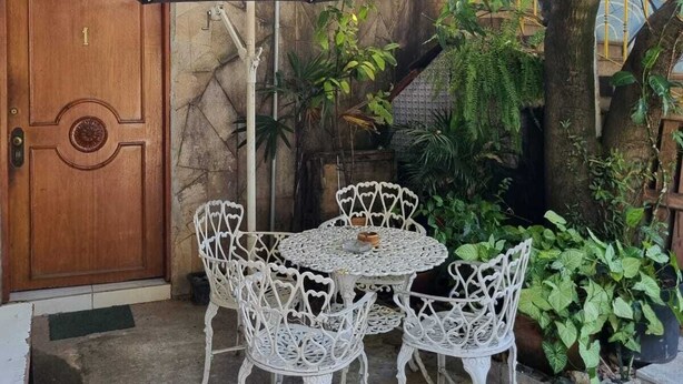 A patio with a table and chairs, an umbrella, and a tree. - Hostel Dumah (São Paulo)