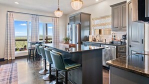 Une cuisine moderne avec un coin bar, de grandes fenêtres et une vue sur l’extérieur.