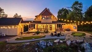 Une maison moderne dotée d’une grande véranda, d’un espace salon extérieur et d’une pelouse bien entretenue.