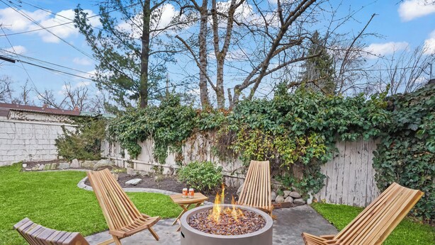 A backyard with a fire pit, wooden chairs, and a small table. - Yard w/ fire pit & grill, king bed, light filled (Boise)