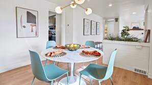 A dining area with a round table, four chairs, a chandelier, and framed artwork on the walls. - Yard w/ fire pit & grill, king bed, light filled (Boise)