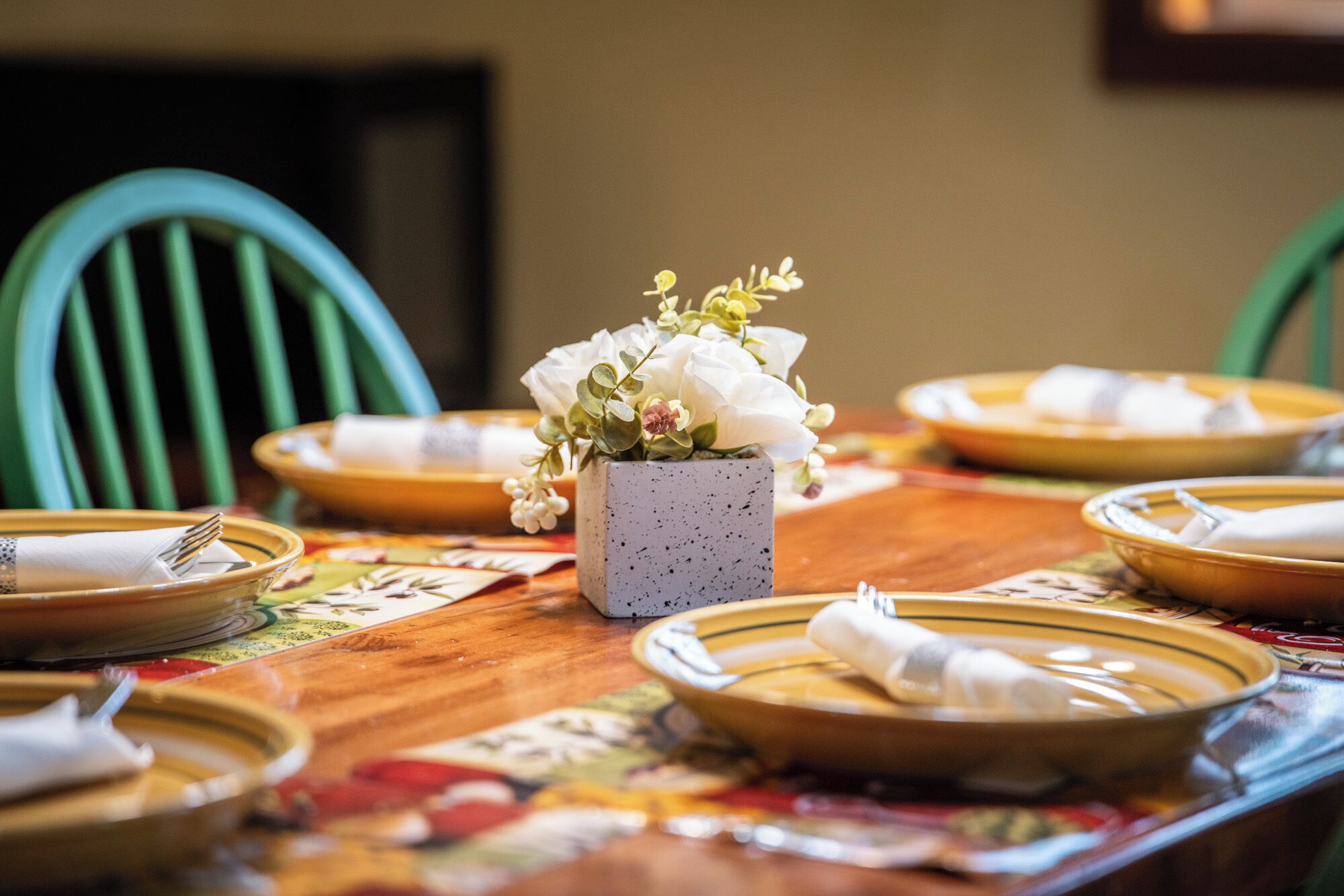 Une table à manger avec des assiettes, des couverts et un centre de table.