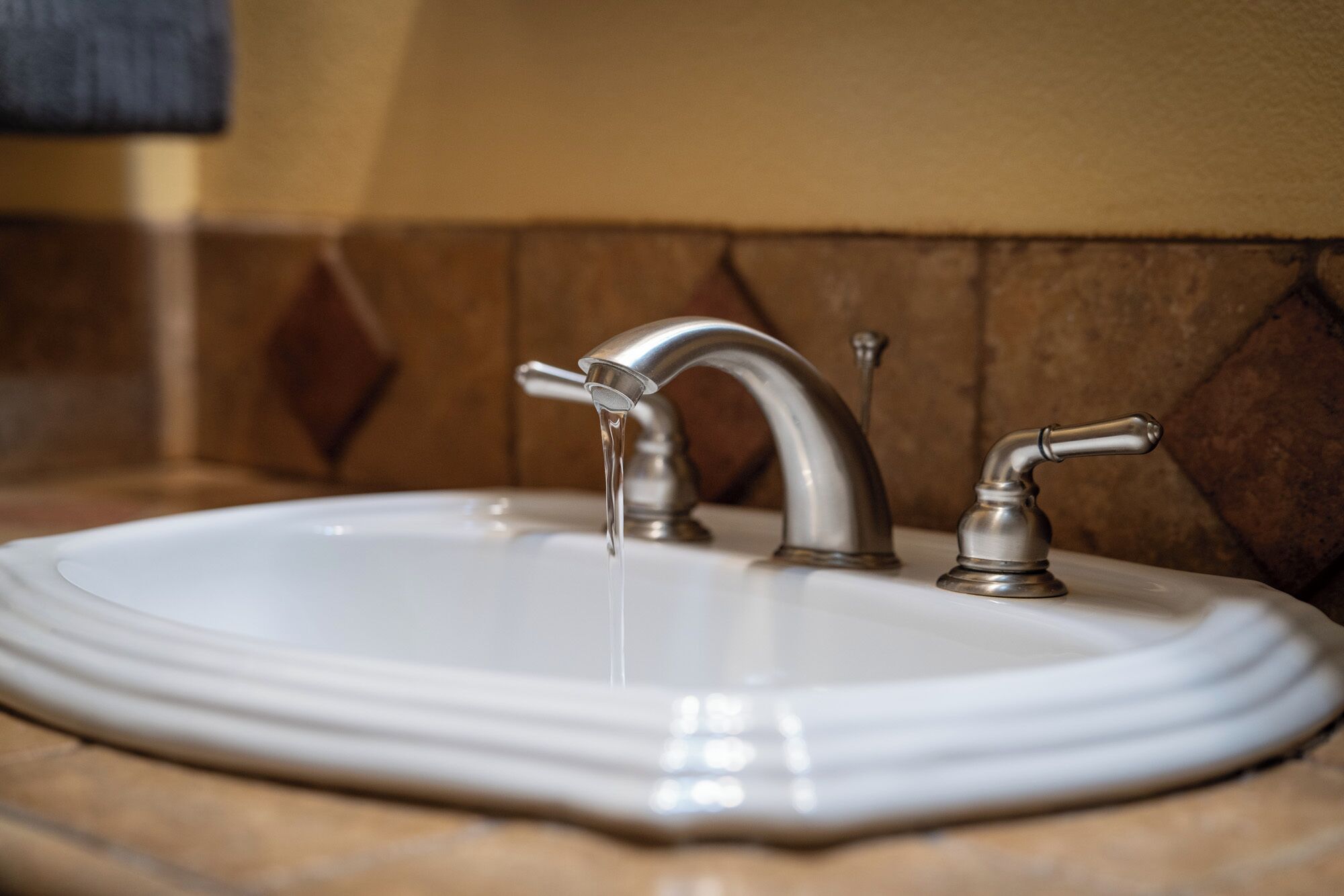 A bathroom sink with a single faucet and a mirror.