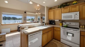 Una cocina moderna con una isla grande, armarios de madera, horno empotrado y vistas a un lago.
