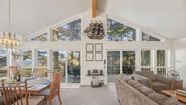 A spacious living area with a high ceiling, large windows, and a cozy seating arrangement.