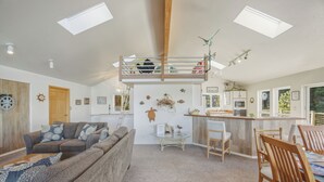 A cozy living room with a sofa, a coffee table, and a dining area with chairs and a table.