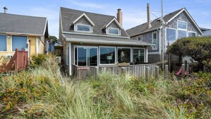 Een huis aan de kust met een grote erker, een omheind terras en een 'Geen toegang'-bord.
