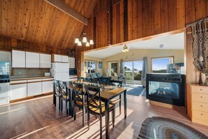 Una cocina amplia con armarios de madera, un comedor con una mesa grande y sillas, y una chimenea.