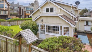 A two-story house with a large front porch, a satellite dish, and a well-maintained garden. - Susan’s Beach Cottage · Cozy Coastal Charm Just 1 Block from the Beach in the Heart of Manzanita (Manzanita)