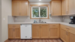 Una cocina moderna con armarios de madera, lavavajillas integrado y cafetera.