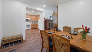 Una cocina moderna con armarios de madera, un microondas y una estufa. Hay un comedor con una mesa y sillas de madera, y un jarrón con flores.