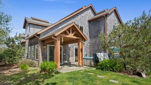 A modern house with a covered patio, a hot tub, and a well-maintained garden.