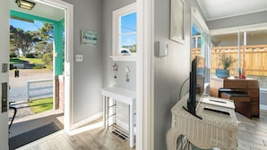 Ein modernes Interieur mit einer weißen Konsole, einem Korbwägelchen und einem Fernseher.