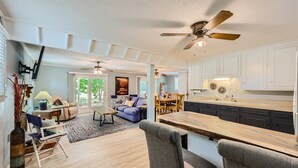 A spacious living room with a large window, a ceiling fan, and a dining area with a wooden table and chairs. - Locke Haven (Sherrills Ford)